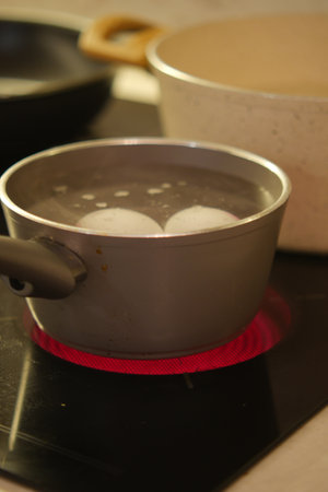Boiling eggs in a metal pot on a cookerの写真素材