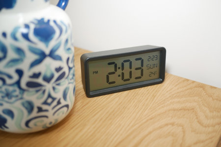 Clock on wooden table next to decorative ceramic jugの写真素材