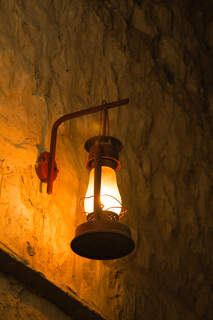Lantern illuminating rustic stone wall in dim lightの写真素材