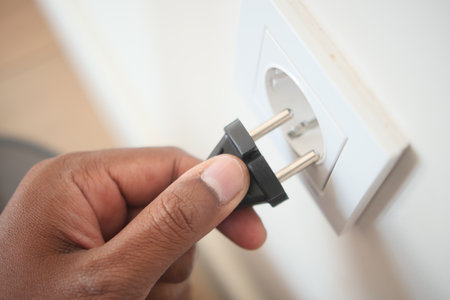 Hand inserting plug into electrical outlet in a homeの写真素材