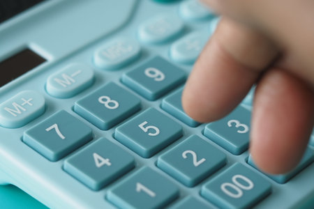 Pressing buttons on a teal calculatorの写真素材