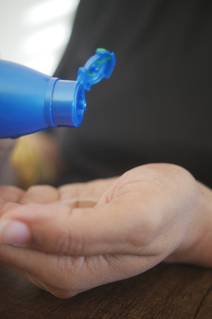 Hand applying hair oil in a bright indoor settingの写真素材