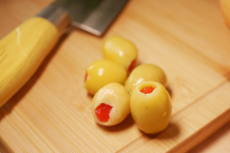 Stuffed olives on a wooden cutting board with knifeの写真素材