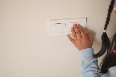 Child turning on lights at home during the dayの写真素材