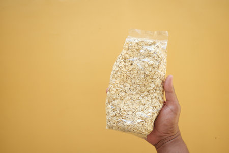 Packaged oats held against a yellow backgroundの写真素材