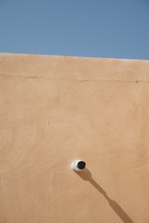 Wall with a security camera against a clear blue skyの写真素材