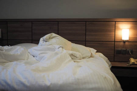 Cozy bed with rumpled blankets in a warm hotel room