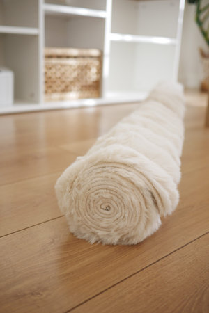 Soft rolled rug on wooden floor in a cozy room settingの写真素材