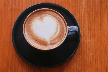 Warm cup of coffee with heart design on cream surface