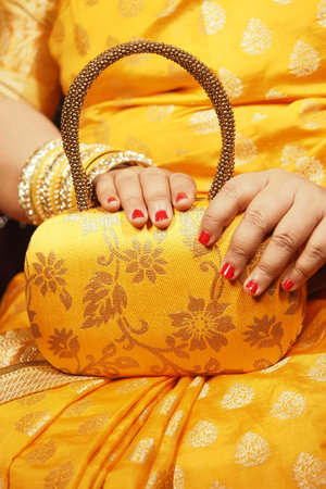 Hands holding a yellow handbag during a festive occasion