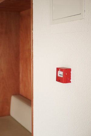 Red alarm box mounted on white wall in minimal spaceの写真素材