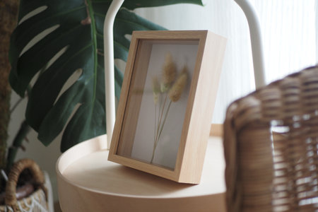 Decorative frame on a wooden table with plant backdropの写真素材