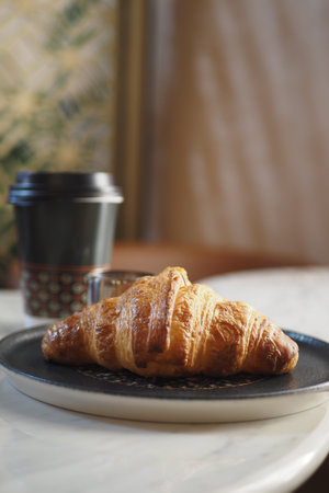 Freshly baked croissant paired with coffee on a tableの写真素材