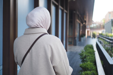 Woman in light scarf walking along urban promenadeの写真素材