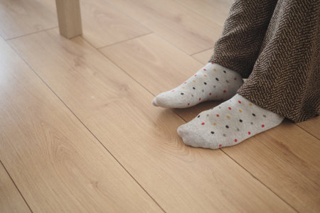 Cozy feet in patterned socks on wooden floorの写真素材