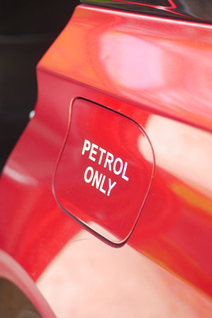Red car fuel cap labeled petrol only in bright sunlightの写真素材