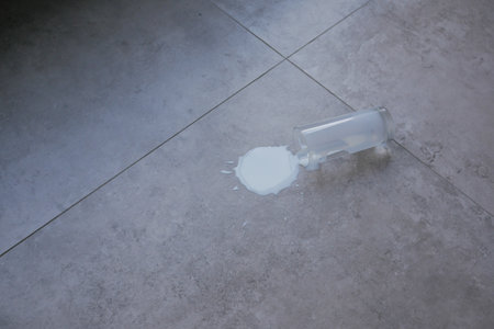milk spilled from a glass on a flat floor surfaceの写真素材
