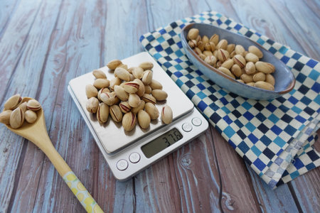 Weighing pistachios on a kitchen scale in a cozy homeの写真素材
