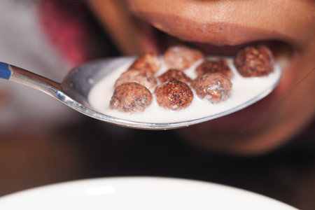 Spoonful of chocolate cereal with milk at breakfastの写真素材