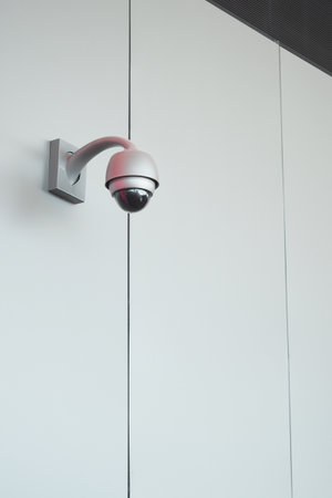 Security camera mounted on a white wall indoorsの写真素材
