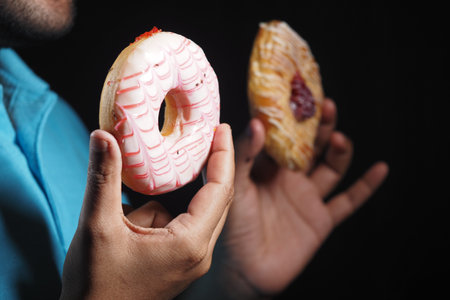Colorful donuts held by a person in dark background