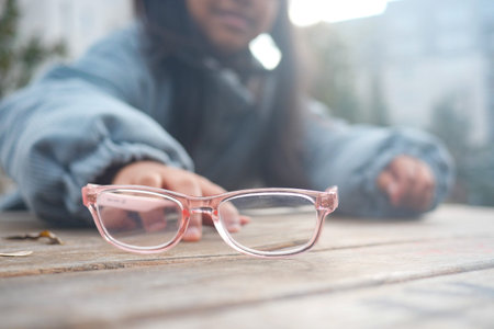 Glasses placed on a table with a person reaching for themの写真素材
