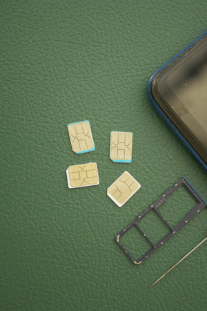 Multiple SIM cards and a smartphone on a green surfaceの写真素材