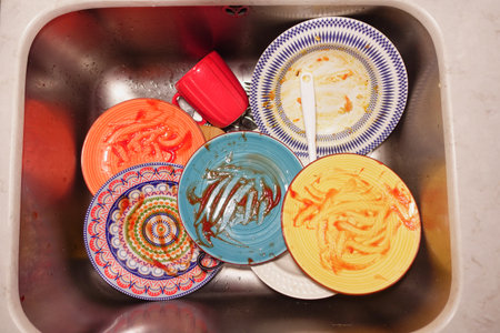 Dirty dishes piled high in a kitchen sink after dinnerの写真素材