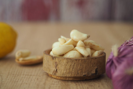 Fresh garlic cloves with lemon and nuts on a wooden tableの写真素材