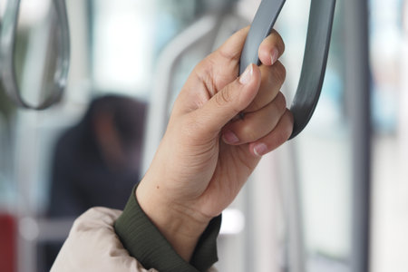 Hand gripping bus pole while commuting in urban setting