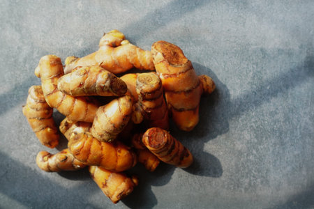 Turmeric roots displayed on a textured grey surface