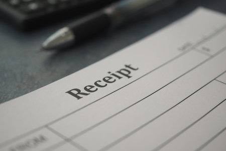 Receipt on a desk with a pen and calculator nearbyの写真素材