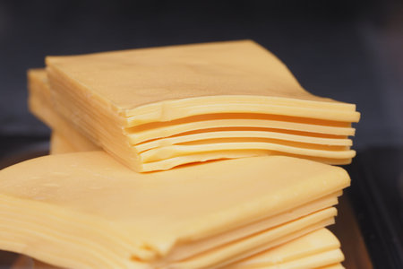 Freshly stacked yellow cheese slices ready for sandwiches