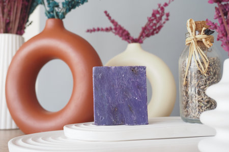 Handcrafted purple soap displayed among stylish decor elements indoors.の写真素材