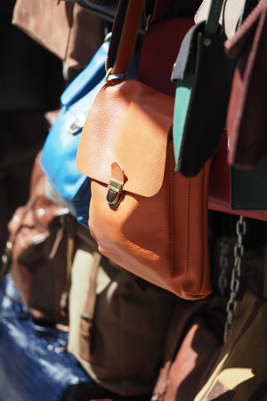 Leather bags in various colors hang from a market stall outdoors.の写真素材