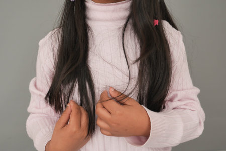 little girl showing long hair in light sweater indoors