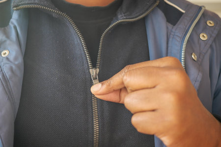 Man zipping up jacket indoors during cool weatherの写真素材