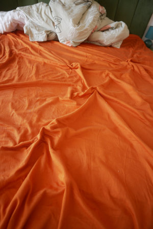 Vibrant Orange Fabric with Wrinkles and Creases in Soft Texture Detailの写真素材