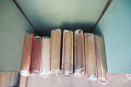 Old books arranged neatly on a shelf in a libraryの写真素材