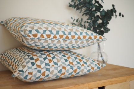 Decorative pillows on a wooden table with greenery