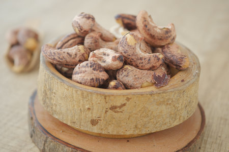 Close-Up of Rustic Cashew Nuts in a Wooden Bowl on a Tableの写真素材