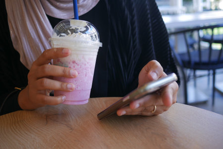 Enjoying a refreshing drink while using a smartphone