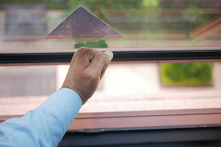 Hand adjusting window pane with outdoor view in daylightの写真素材