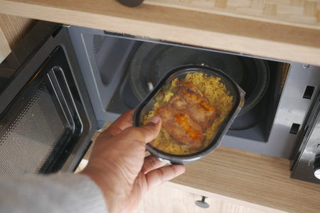 Preparing a meal in a microwave with rice and chickenの写真素材