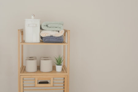 Neatly arranged wooden shelving displays towels, a toilet tissue and a plant