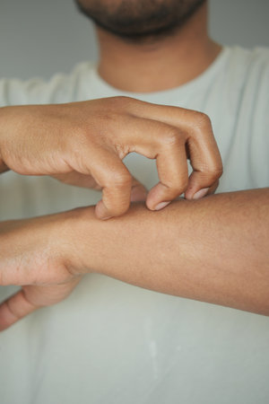 Man scratching his arm in a minimalist indoor settingの写真素材