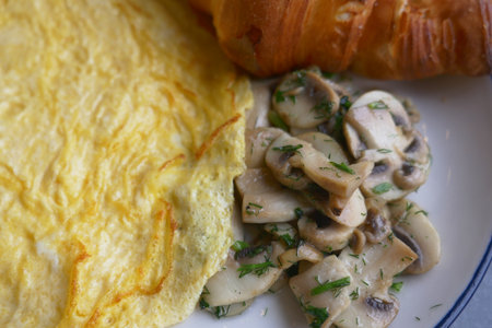 Breakfast spread with omelet, mushrooms, and croissantの写真素材