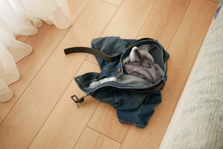 jeans left on wooden floor in a bright room