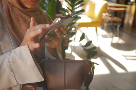 Woman using smartphone in bright cafe settingの写真素材