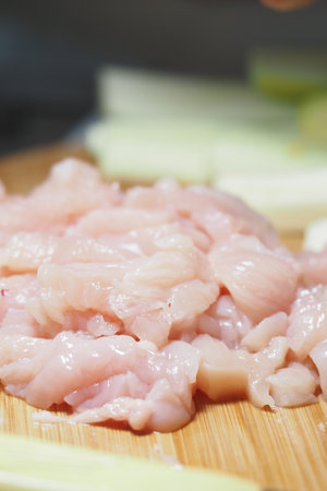 Freshly sliced chicken ready for cooking on a wooden boardの写真素材